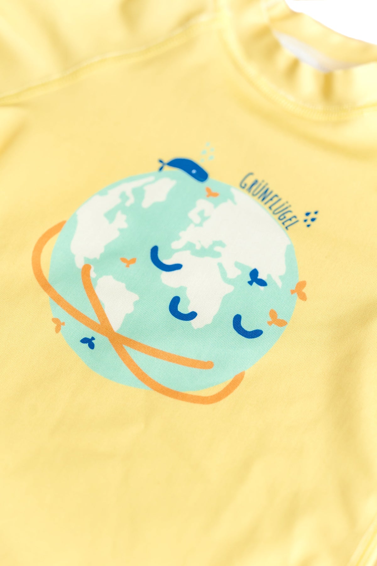 Gelbes Grünflügel UV-Shirt für Kinder – Detailansicht mit Weltkugel-Print