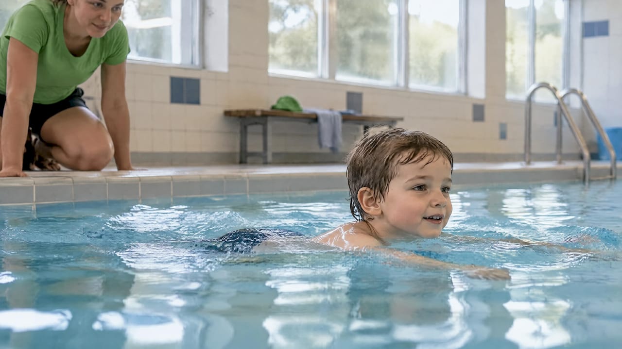 Kind schwimmt unter Aufsicht ohne Schwimmhilfe